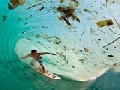 Surfer Gliding Through Trash-Filled Wave
